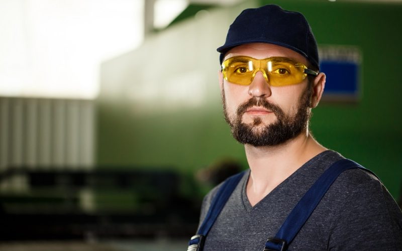 Portrait of worker in overalls, industrial steel factory background.