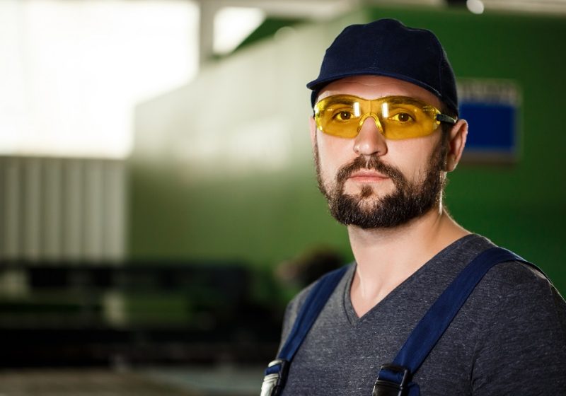 Portrait of worker in overalls, industrial steel factory background.